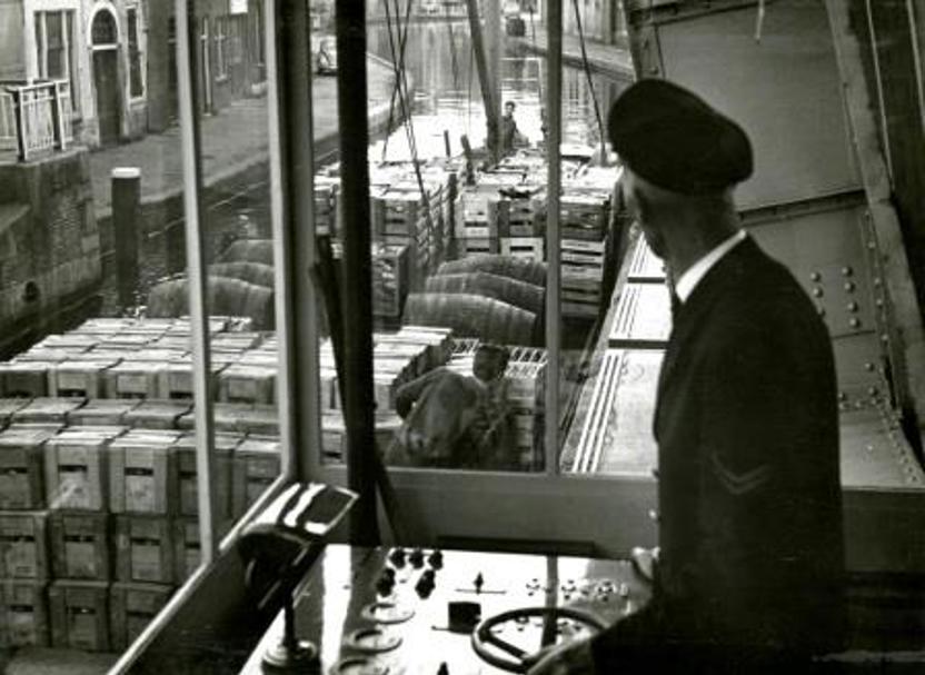 De brugwachter aan het bedieningspaneel in het brugwachtershuisje van de Ooievaarsbrug over de Schie in Schiedam, 1962 (Foto H. Visser, Collectie Gemeentearchief Schiedam)