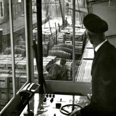 De brugwachter aan het bedieningspaneel in het brugwachtershuisje van de Ooievaarsbrug over de Schie in Schiedam, 1962 (Foto H. Visser, Collectie Gemeentearchief Schiedam)